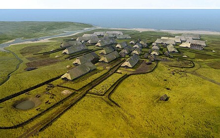 Lebensbild der Feddersen Wierde farbige Darstellung der rekonstruierten Siedlung, um einen Zentralplatz sieht amn kreisförmig angelegte Häuser und Zäune