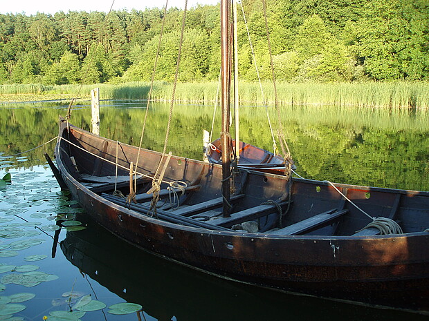 Rekonstruiertes Holzboot am Ufer eines Flusses